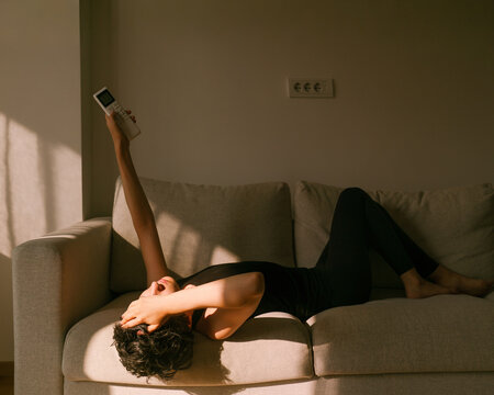 Person Relaxing on a Couch While Holding a AC Remote Control