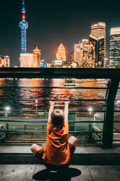 Child looks at Shanghai skyline and river at night