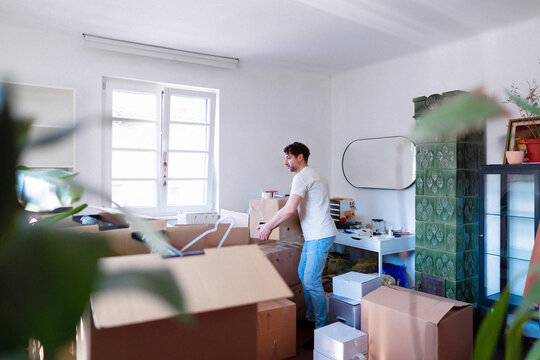 Man Packing Boxes During Move In Bright Apartment
