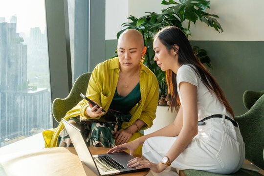 Two Women Work Together on a Laptop in a City Building