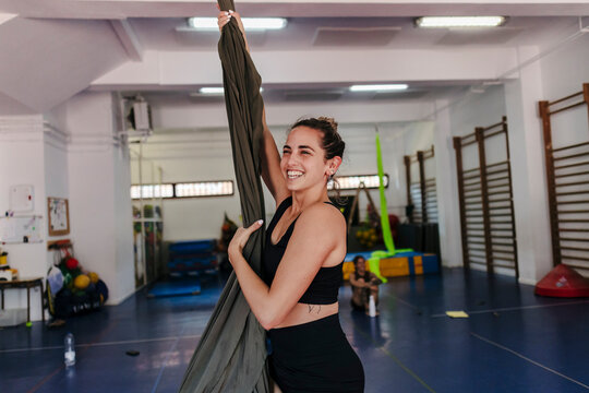 Young woman smiling while practicing aerial silks