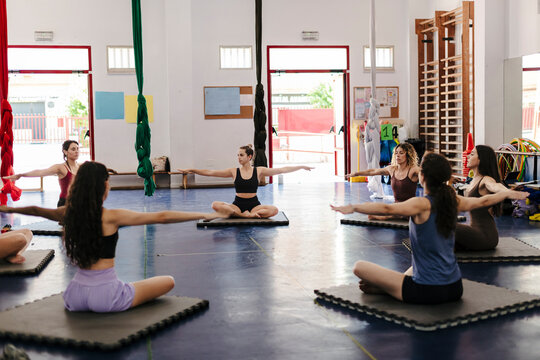 Young women training practicing yoga stretching exercise in gym