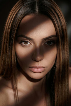 Dramatic close-up portrait of beautiful woman with shadow casting across her face.