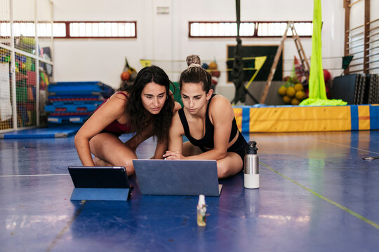 Two women athletes training online using laptop