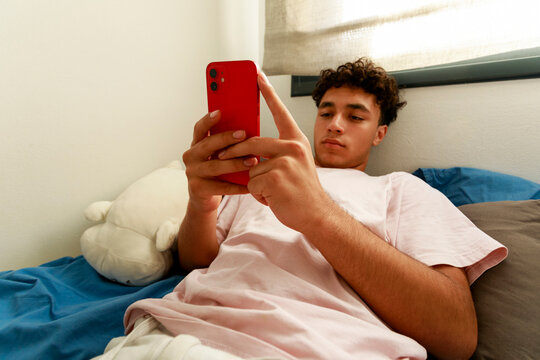 Young Boy Uses Phone in Bedroom