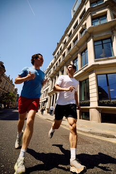 Men jog side by side on a street in downtown London
