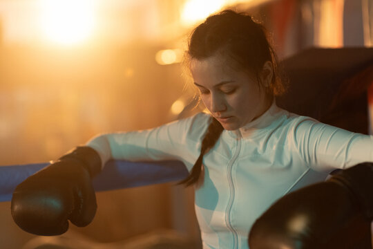 Female boxer rests between sparring rounds in boxing club