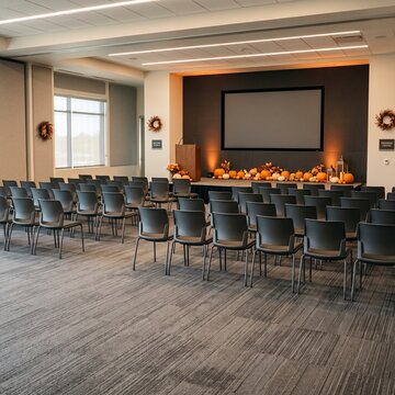 Modern Corporate Training Room with Subtle Halloween Decor, Blank Screen, Warm Lighting, and Ample Copy Space