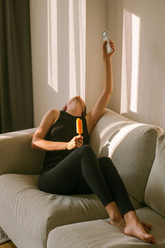 Woman Enjoying Ice Cream and turn on AC in a Living Room