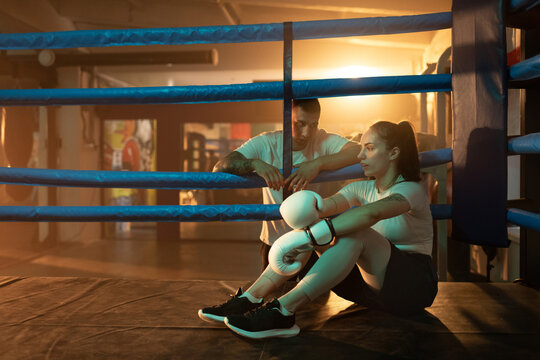 Boxer woman listens to trainer guide in the ring between rounds