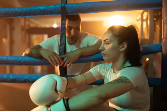 Female boxer listens to coach during break between the fight rounds