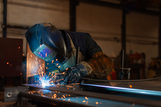 Skilled industrial worker performing precision welding in metal workshop
