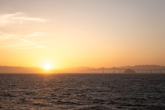 Beautiful Sunset Over the Water and Bridge in the Distance