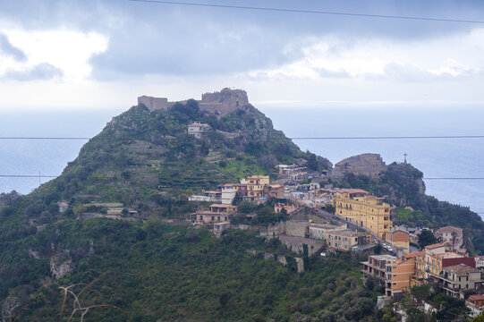 Ruins of Saracen castle crown the summit of Monte Tauro high above the coastal town of Taormina in Sicily. Concept of medieval fortification history and dramatic mountaintop landmark photography.
