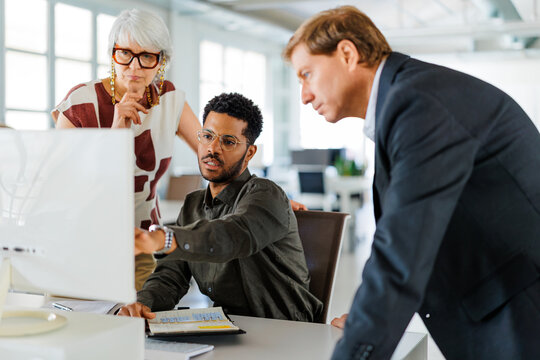 Business team discussing work on computer screen at office desk