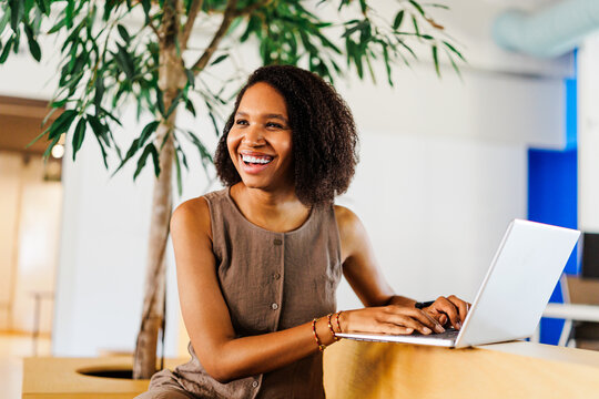 Happy woman working on laptop in modern office