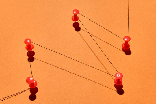 Red Push Pins Connected by Thread Symbolizing Human Relationships
