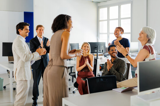 Business professionals applauding colleague speaker during meeting