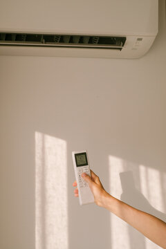 Person Uses Remote Control to Adjust Air Conditioner Settings