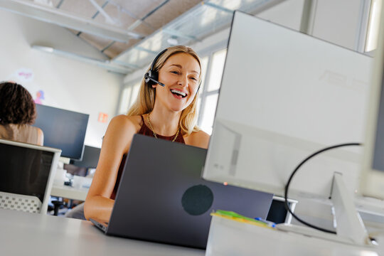 Woman laughing while working at a computer in a modern office