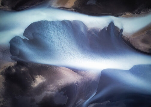 Aerial view of a braided glacial river flowing through dark volcanic sand in the Southern Region of Iceland.