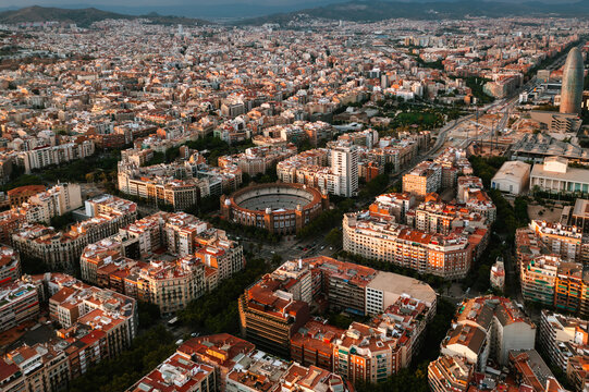 Aerial view of the Monumental Bullring of Barcelona surrounded by dense urban architecture and residential blocks in the golden light of late afternoon in Barcelona, Catalonia, Spain.