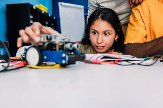 latina young university woman student working on a robotics project and car robotics in classroom. Hispanic girl in technology class in an Academic Environment in Latin America