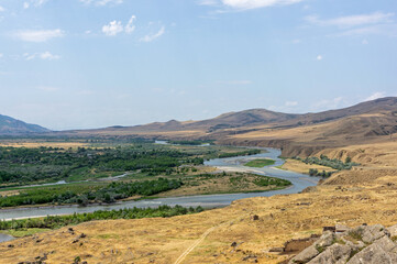 Scenic view of Mtkvari (Kura) River winding through arid hills and green valley near Uplistsikhe, Georgia © MikhailT