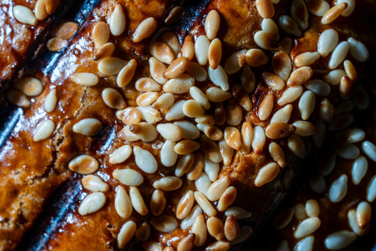 Full frame macro closeup of crispy golden brown baked pastry crust topped with toasted white sesame seeds food texture background for bakery marketing and culinary design