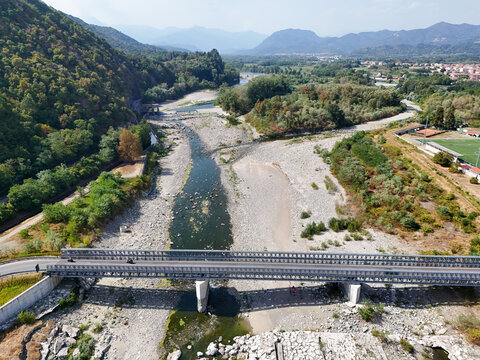 Aerial view of the Sesia River showing significant drought with a dry riverbed and exposed stones under a bridge in Vercelli, Piemonte, Italy.