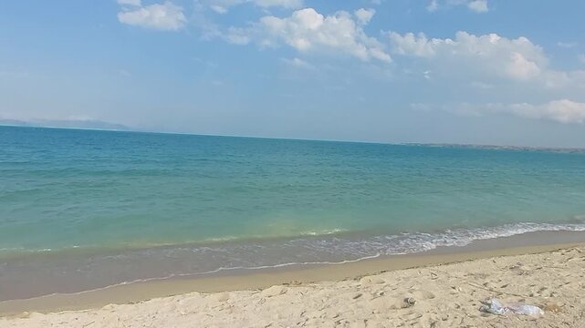 Scenic sandy beach and turquoise blue water waves on Lake Sevan Armenia. Beautiful tropical style sandy beach with gentle turquoise water waves rolling ashore at Lake Sevan in Armenia, sunny summer da