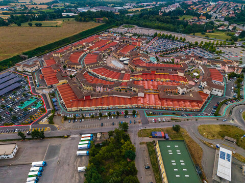 Aerial view of Designer Outlet Serravalle with its red-roofed buildings and parking lots in Serravalle Scrivia, Piemonte, Italy.
