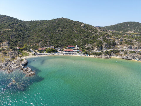Aerial view of Sykias Beach with turquoise waters, rocky coastline, and surrounding hills in Paralia Sikias, Greece.
