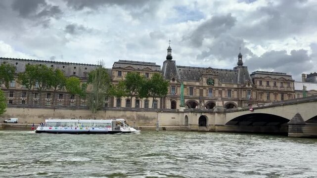 Scenic view of the historic Parisian architecture along the banks of the Seine River in Paris, France, featuring traditional European apartment buildings, stone bridges, and calm water under a dramati