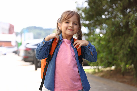 Portrait of happy little girl with backpack outdoors