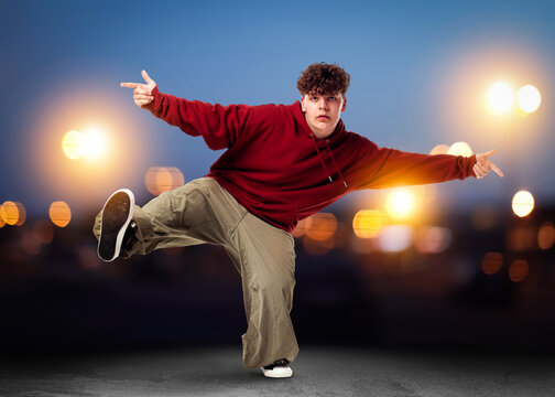 Young man dancing hip-hop on city street at night