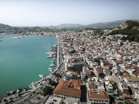Aerial view of the coastal town of Zakynthos with its harbour filled with yachts and boats, terracotta rooftops, and historic buildings along the waterfront in Zakynthos, Greece.