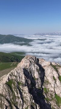 Vertical 4K UHD Drone Flight Above Rocky Mountain Ridge and Sea of Clouds at Sunrise.