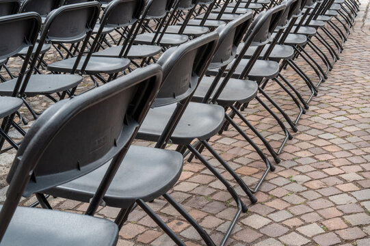 Empty black folding chairs arranged on cobblestone street