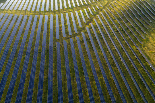 Aerial view of a large solar farm with rows of solar panels installed on a grassy field in Poland.