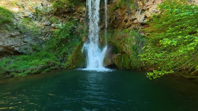 Water cascades into calm, emerald pool below. Veliki Buk, Serbia.