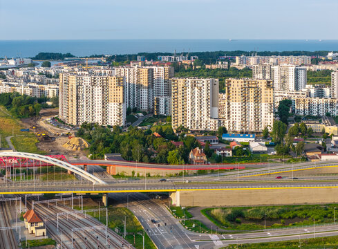 Aerial view of Letnica district with modern high-rise apartment buildings, a red arch bridge over the highway, and railway tracks in Gdansk, Pomeranian Voivodeship, Poland.