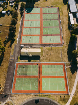 Aerial view of multiple green netball courts with red borders and a small clubhouse surrounded by trees in Devonport, Tasmania, Australia.