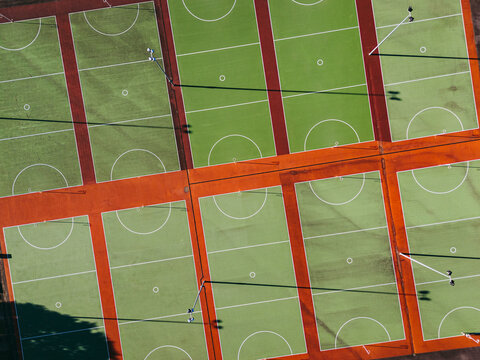 Aerial view of multiple green sports courts with red borders and white markings under bright sunlight in Devonport, Tasmania, Australia.
