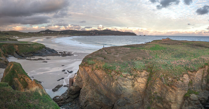 Aerial view of Ermita de Santa Comba on a rocky headland overlooking the sandy beach and Atlantic Ocean under a dramatic cloudy sky Covas, La Coruna, Spain.