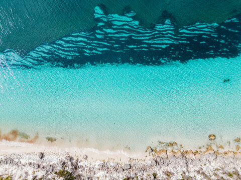 Aerial view of the turquoise waters and rocky coastline of Flinders Peninsula, featuring clear shallow water, sandy beach, and rugged rocks in Torndirrup, Western Australia, Australia.