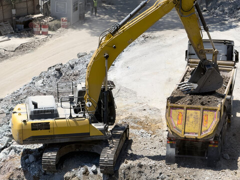 View of a yellow excavator loading soil into a dump truck at a construction site in Istanbul, Istanbul, Turkiye.