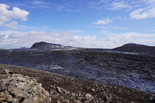 View of the solidified lava fields of Fagradalsfjall Volcano with rugged volcanic terrain under a blue sky with scattered clouds near Grindavik, Grindavikurbaer, Iceland.