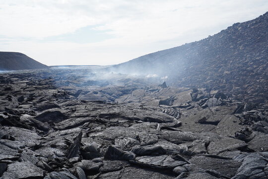 View of the solidified black lava field at Fagradalsfjall Volcano with steam rising from the volcanic terrain in Grindavik, Grindavikurbaer, Iceland.