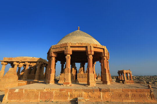 View of the historic Chaukhandi Tombs with intricate sandstone carvings under a clear blue sky in Karachi, Sindh, Pakistan.